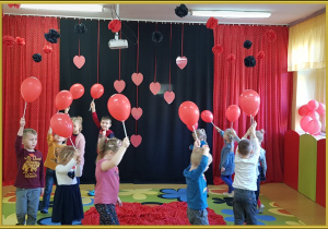 Dzieci trzymają balony. Bawią się przy muzyce.
